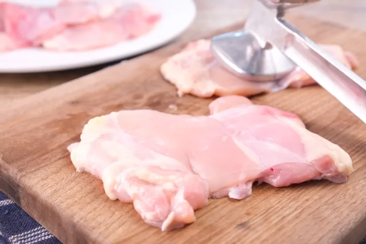 Pounding chicken filets using a meat mallet.