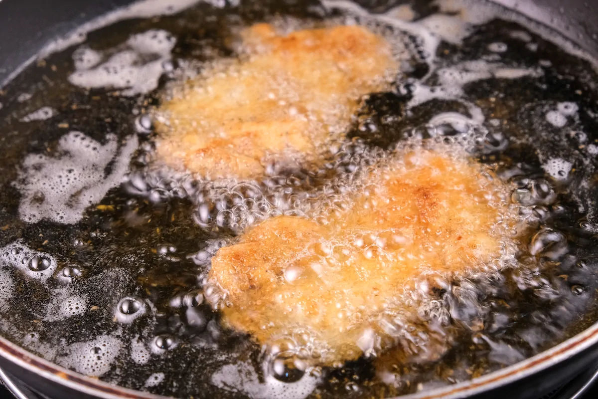 Frying chicken fillets in ghee in a cast iron skillet.