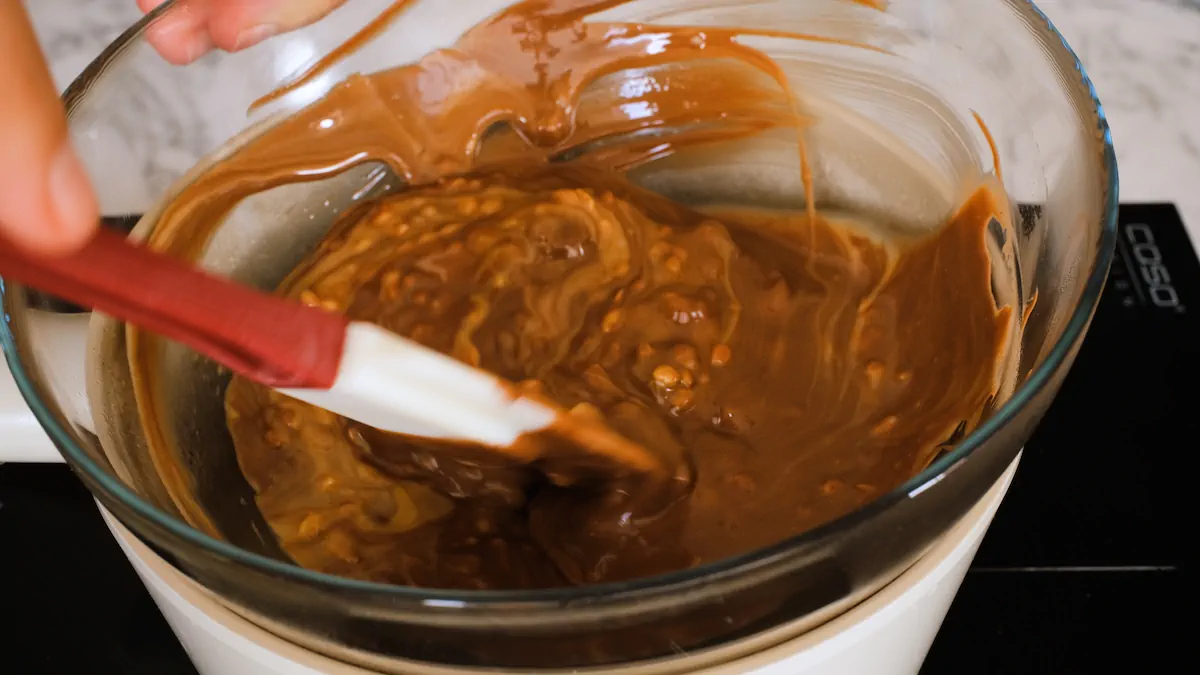 Mixing a mixture of peanut butter and melted chocolate with a spatula over a double boiler.