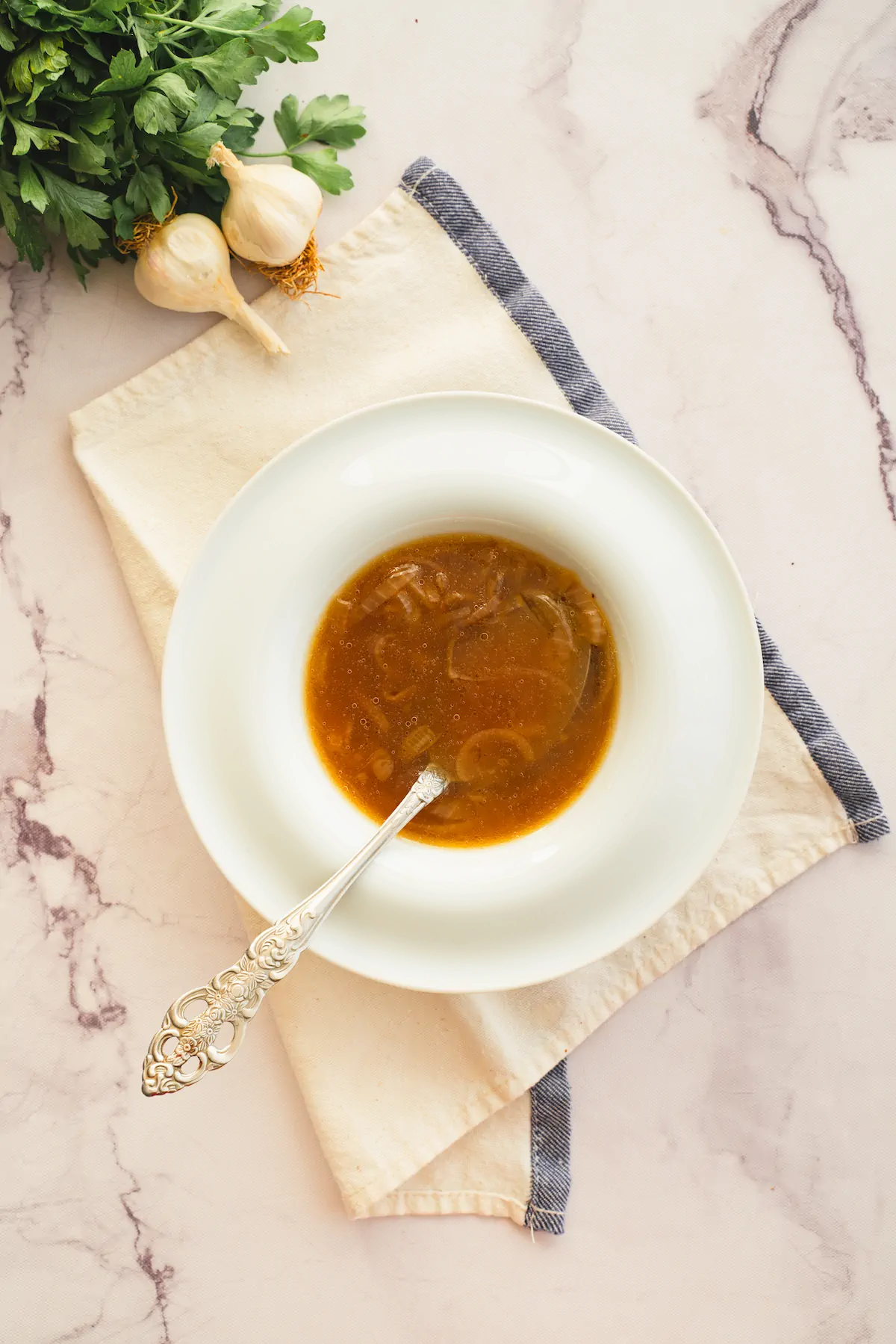 Keto French onion soup is served in a white bowl with a spoon.