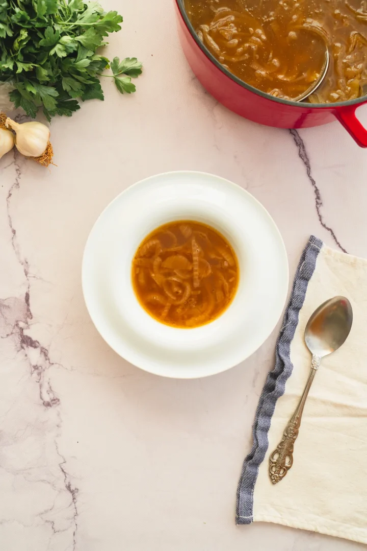Keto French onion soup in a bowl alongside a spoon.