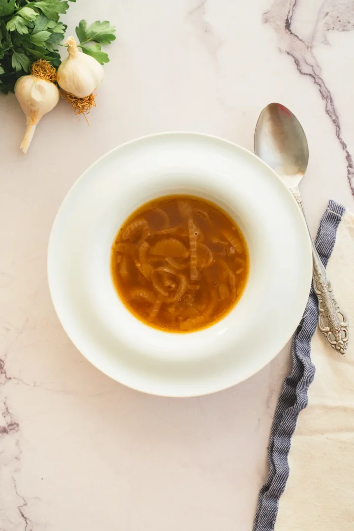 Homemade French onion soup served in a white bowl with a spoon.