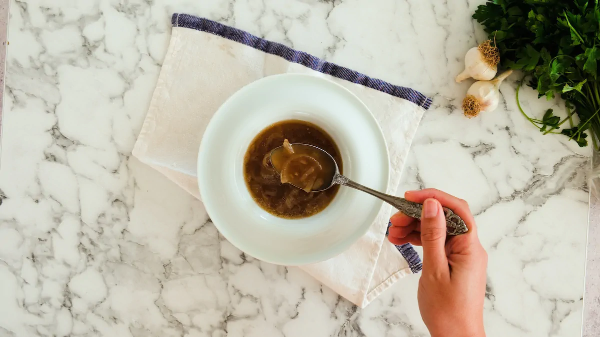 Scooping a spoonful of homemade keto French onion soup from a bowl.