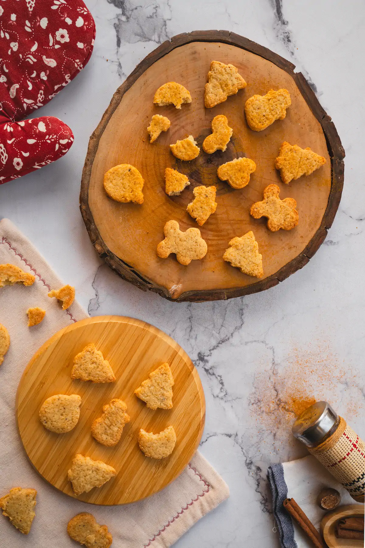 Keto gingerbread cookies are placed on a wooden board, and a few are broken to reveal their texture.