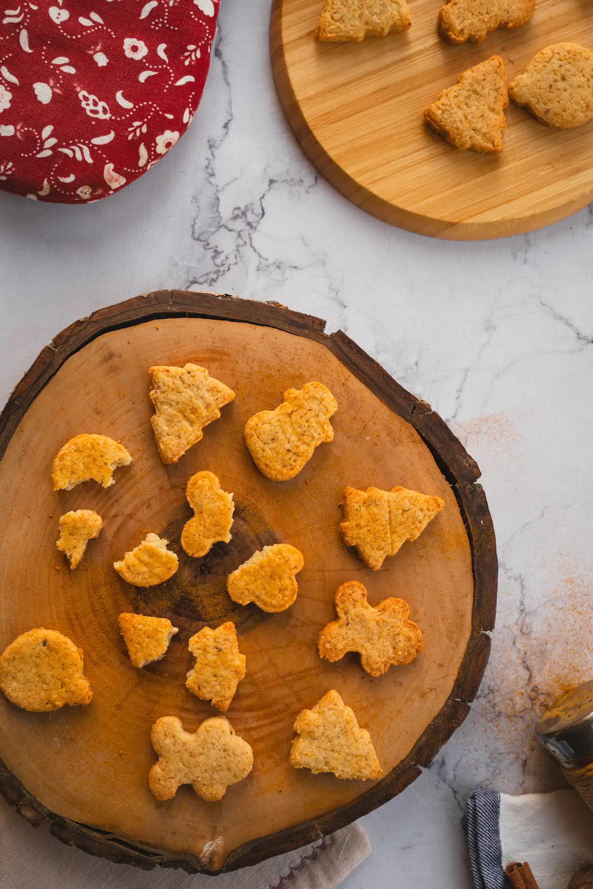 Keto gingerbread cookies are arranged on a wooden board, with a few intentionally broken to highlight the texture.