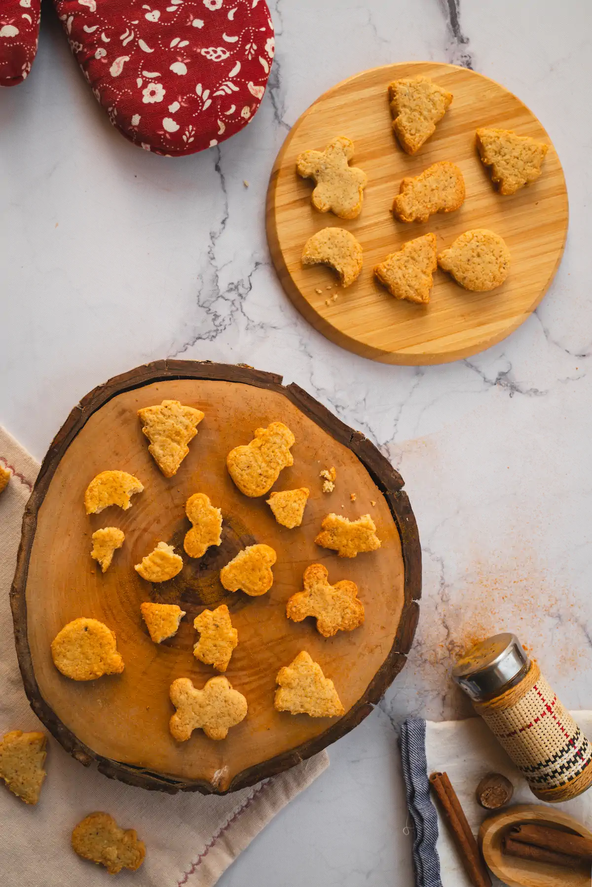 Keto gingerbread cookies are arranged on a wooden board, with some deliberately broken to reveal the texture.