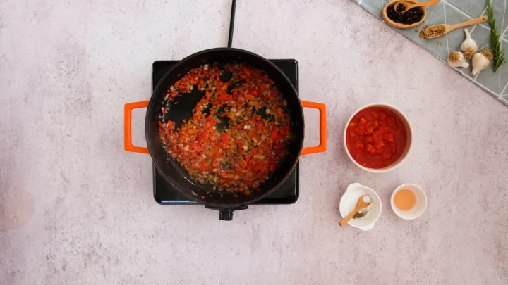 Sautéing the diced onions, bell peppers and minced garlic in a cast iron skillet.