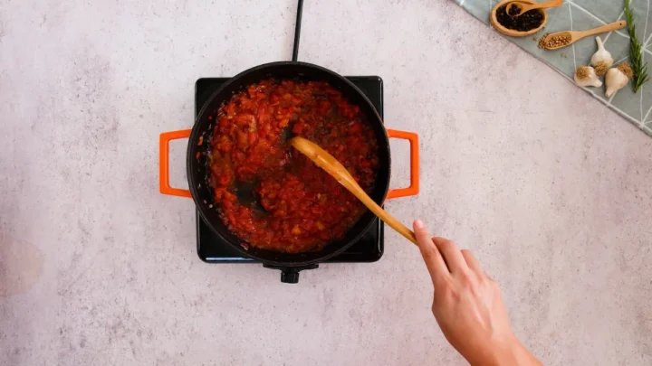 Cooking the chopped tomatoes with the aromatics in a cast iron skillet.