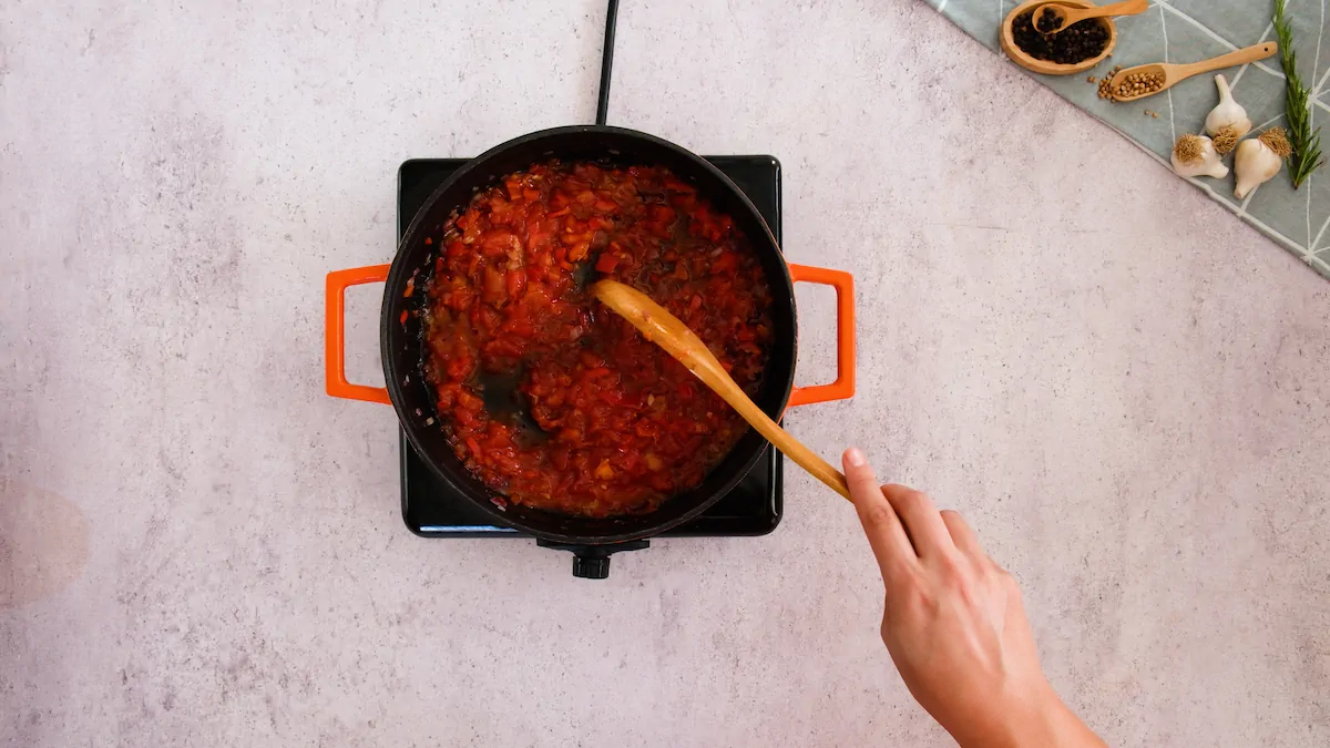 Cooking the chopped tomatoes with the aromatics in a cast iron skillet.