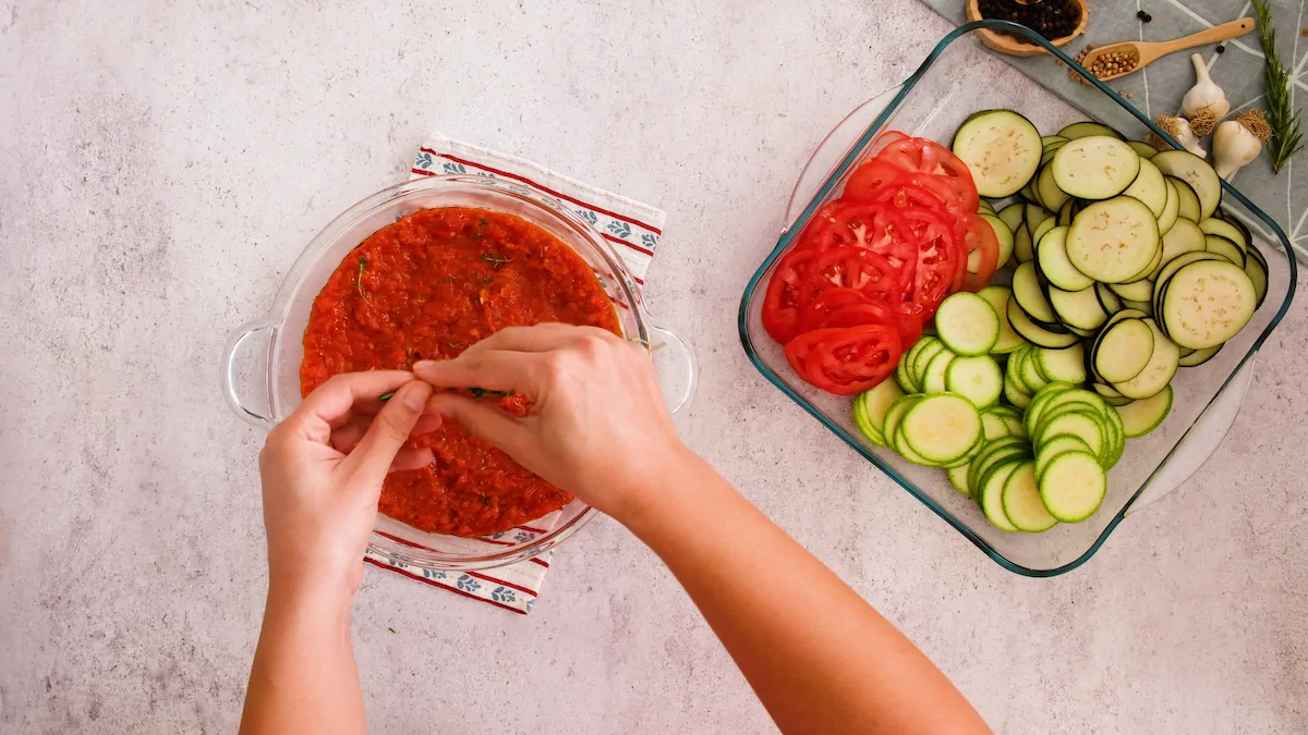 Adding the fresh thyme leaves over the sauce in a baking dish.