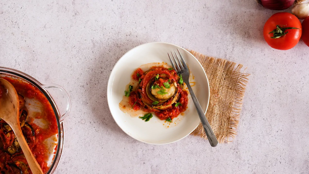 Keto ratatouille served on a plate with a fork and garnished with fresh herbs.