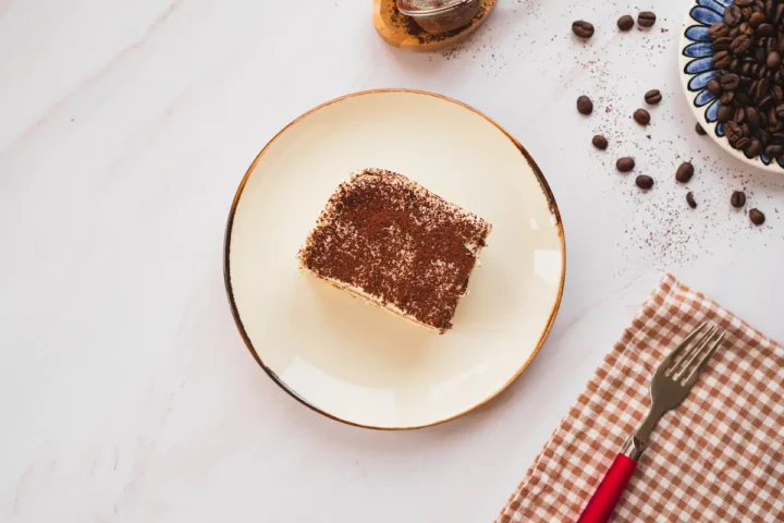 Keto tiramisu, dusted with cocoa powder, is presented on a plate.
