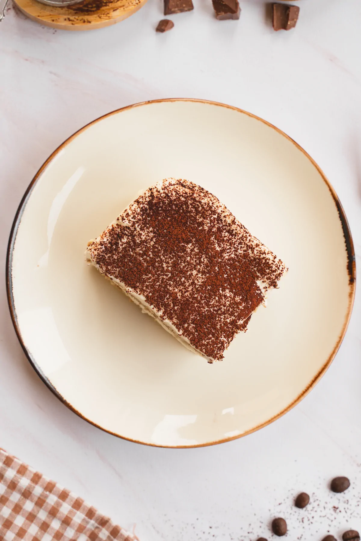 Homemade keto tiramisu, with a cocoa powder dusting, is served on a plate.