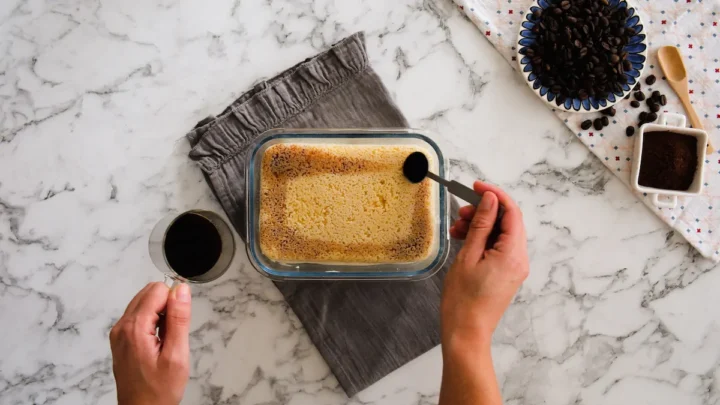 Pouring coffee shots onto the top layer of the tiramisu.