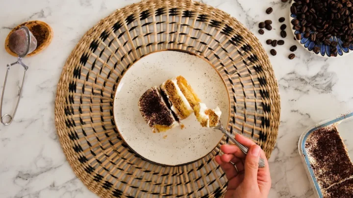 Keto tiramisu on a plate, layers visible, and a spoonful ready to eat.