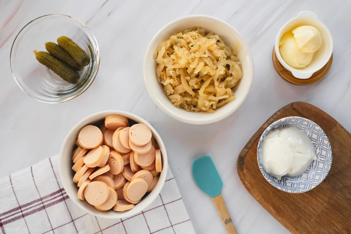 All the ingredients required to make sausage and sauerkraut gathered and arranged on the table.