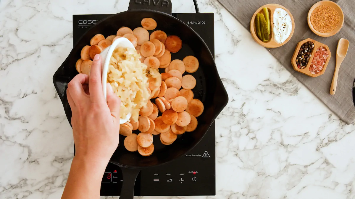 Adding sauerkraut to the skilled with sausages.