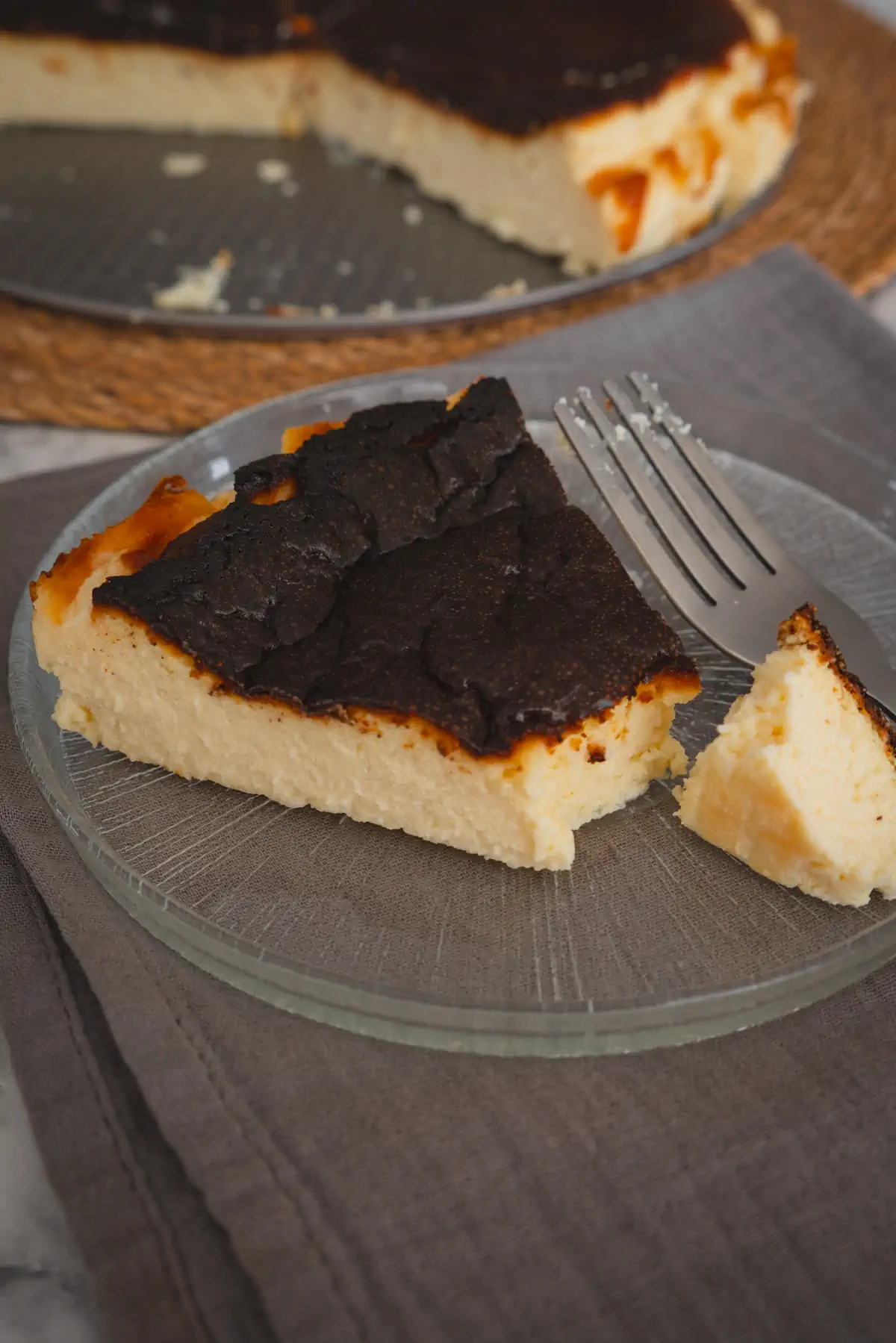 A slice of burnt Basque cheesecake served on a plate and cut with a fork showing the texture.