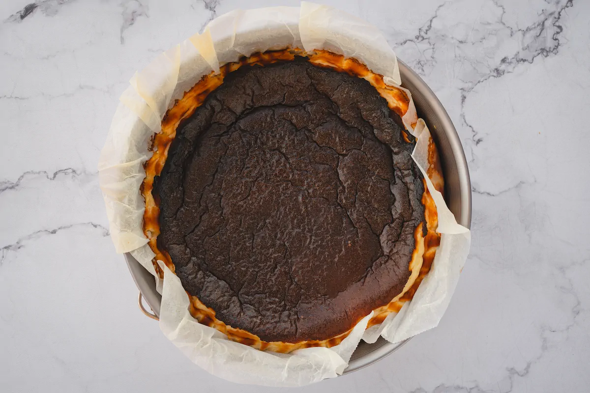 Freshly baked sugar-free keto burnt Basque cheesecake in a a parchment-lined springform mold.