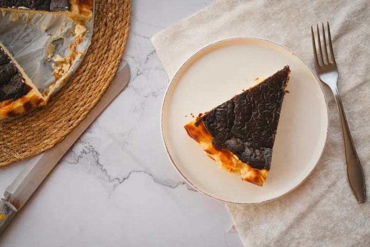 A slice of burnt Basque cheesecake presented on a white plate.