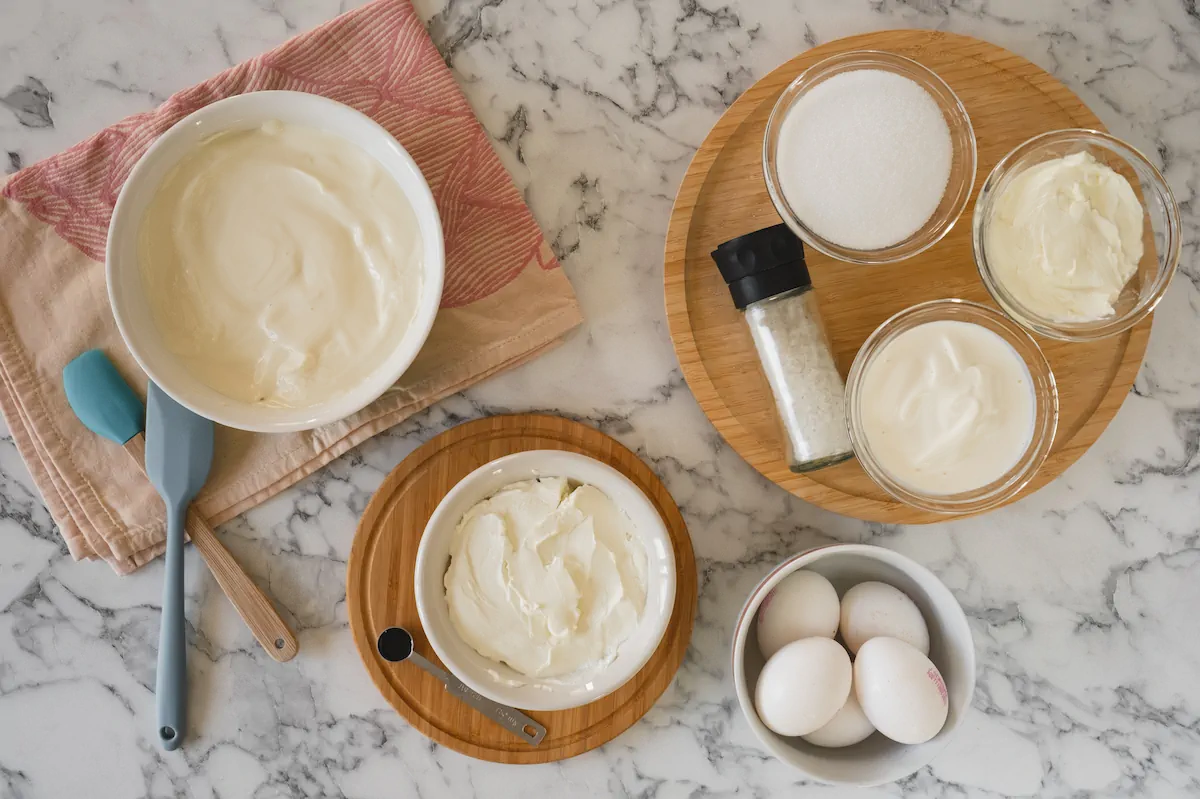 All the ingredients required to make sugar-free cheesecake gathered and arranged on the table.