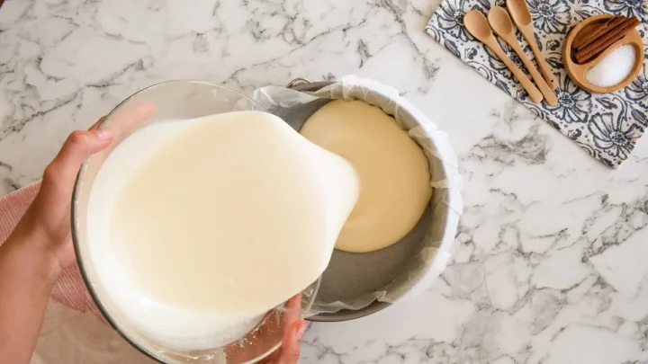 Pouring the cheesecake mixture in a parchment-lined springform mold.