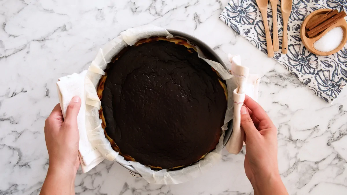 Freshly baked Basque cheesecake, held in a kitchen towel.