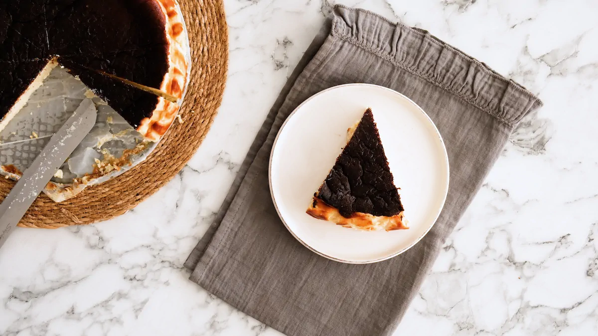 A slice of burnt Basque cheesecake served on a plate, taken from the entire cake.