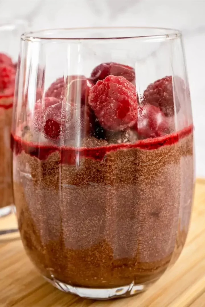 Keto mousse in a glass topped with cherries and berries.