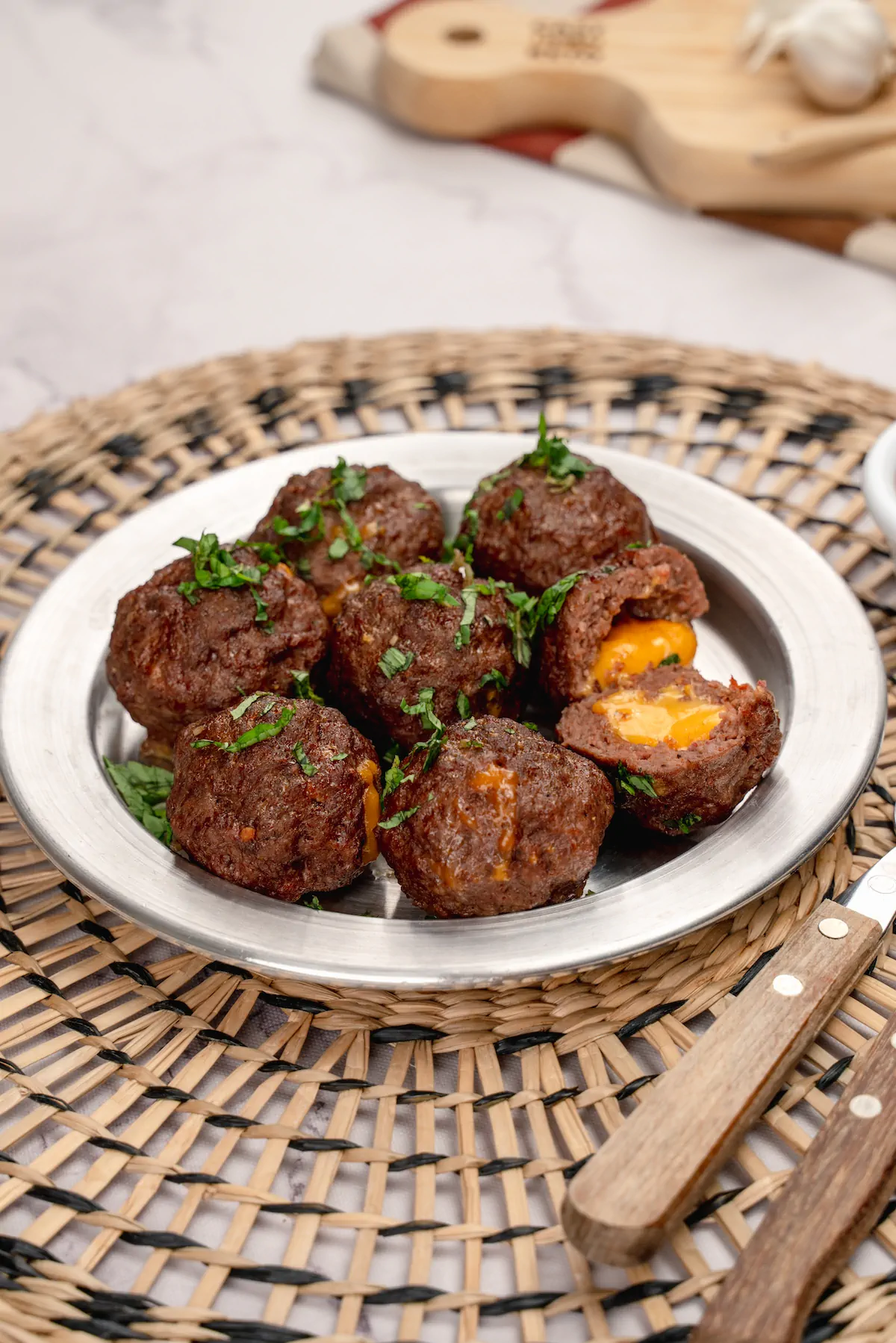 Low-carb cheese-stuffed meatballs on a plate, with one cut open to show the melted cheese.