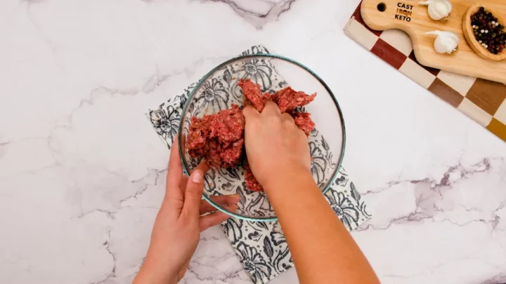 Combining ground beef with sea salt, black pepper, garlic powder, and paprika in a mixing bowl.