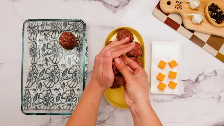 Shaping meatballs with cheddar cheese on a palm.