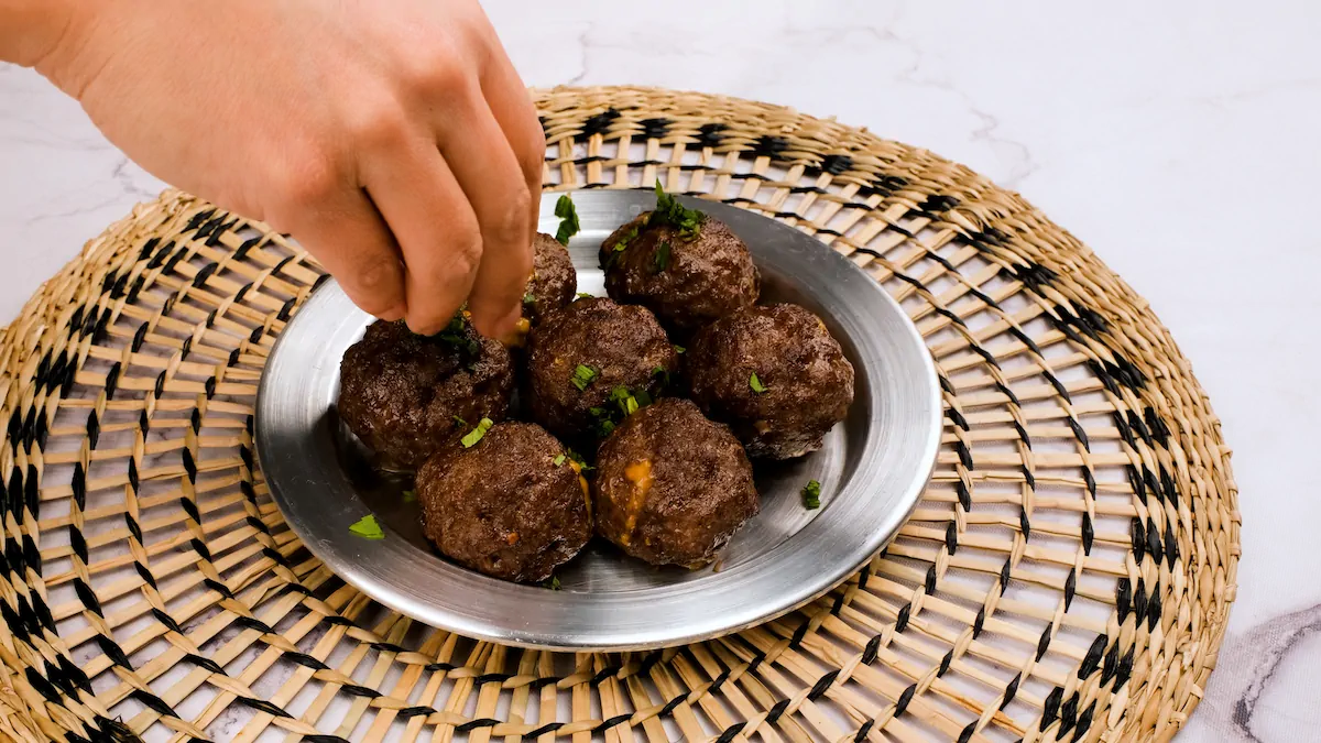Garnishing cheese stuffed meatballs with fresh herbs.