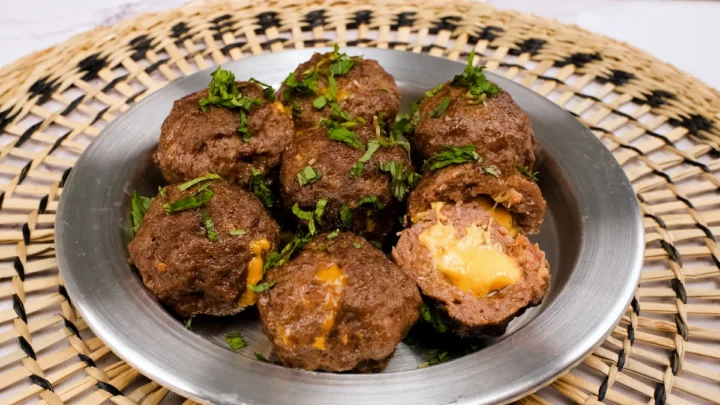 An up-close shot of cheese-filled meatballs served on a plate.