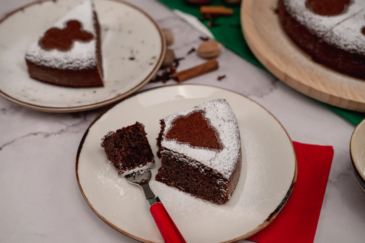 Sugar-free keto gingerbread cake presented on two plates and sprinkled with powdered erythritol.