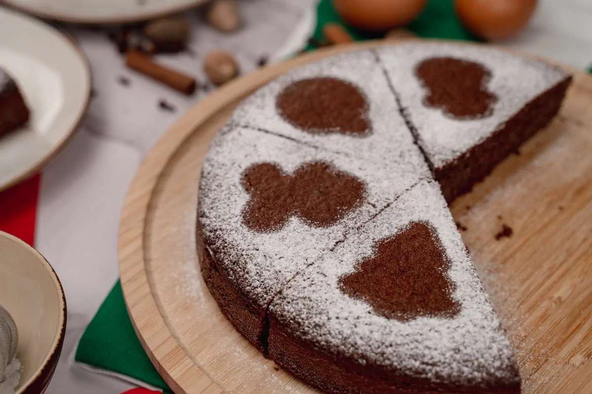 Keto gingerbread cake with a sprinkle of powdered erythritol, and a few slices taken.