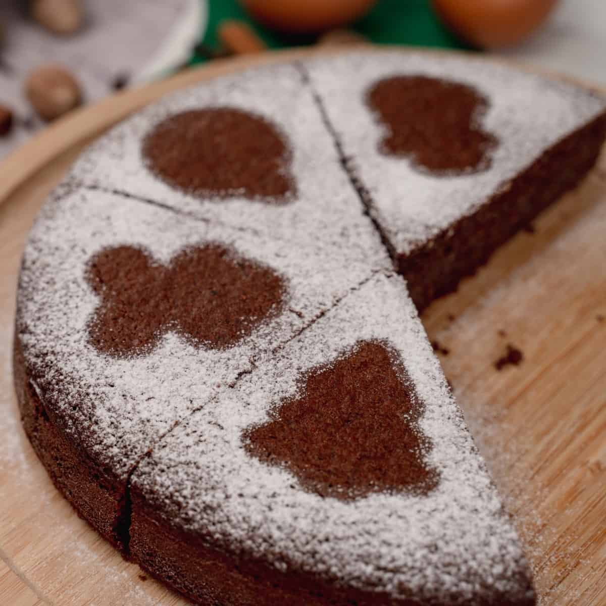 A round keto gingerbread cake dusted with powdered erythritol, where few slices are missing.
