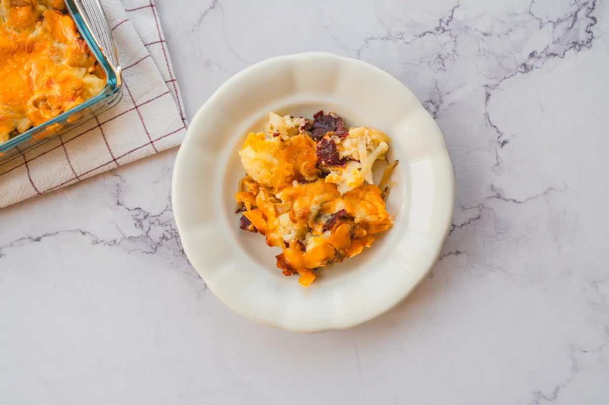 Homemade loaded cauliflower casserole served on a white plate.