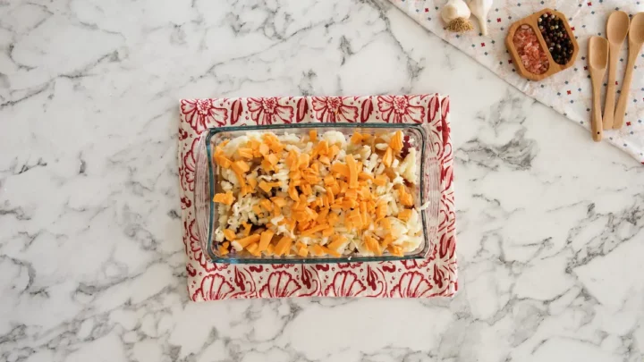 Loaded cauliflower casserole in a glass baking dish almost ready to be baked.