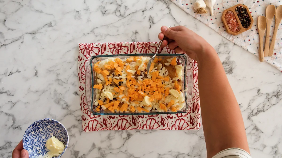 Adding small pieces of butter over the cheese layer of keto loaded cauliflower casserole ready to be baked.