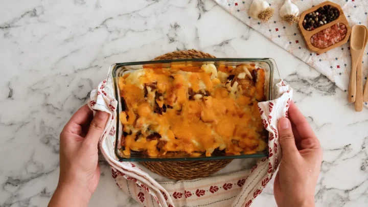 Two hands holding the freshly baked loaded cauliflower casserole.
