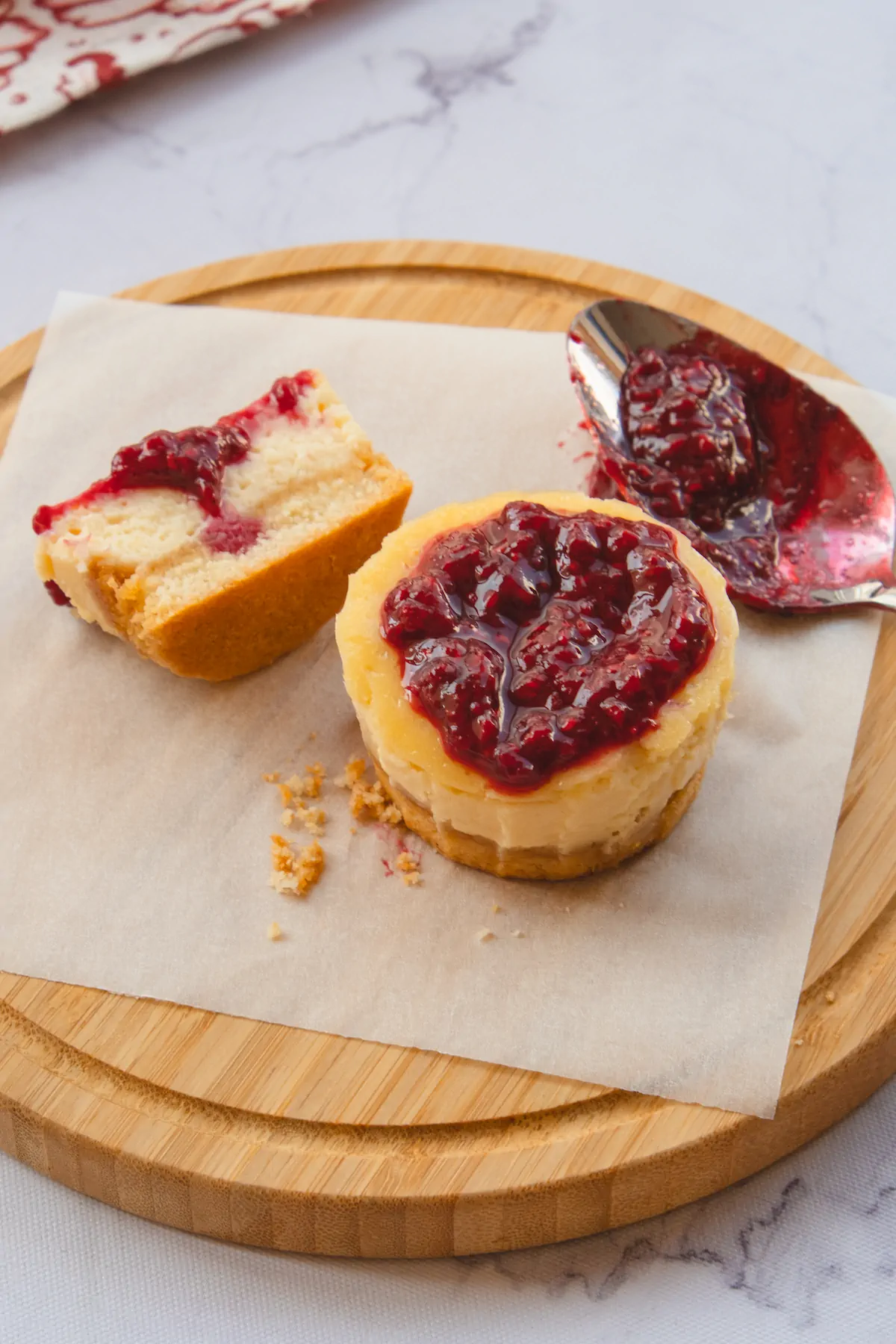 Low-carb mini cheesecake bites topped with raspberry jam and one cut into half revealing the texture.