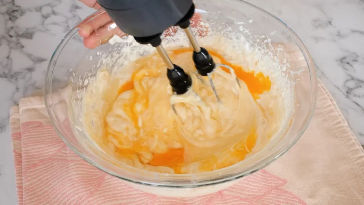 Close-up shot of making cheesecake filling with hand mixer.