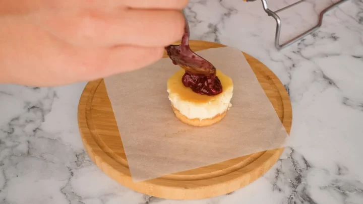 Topping the mini cheese cake bites with keto raspberry jam.