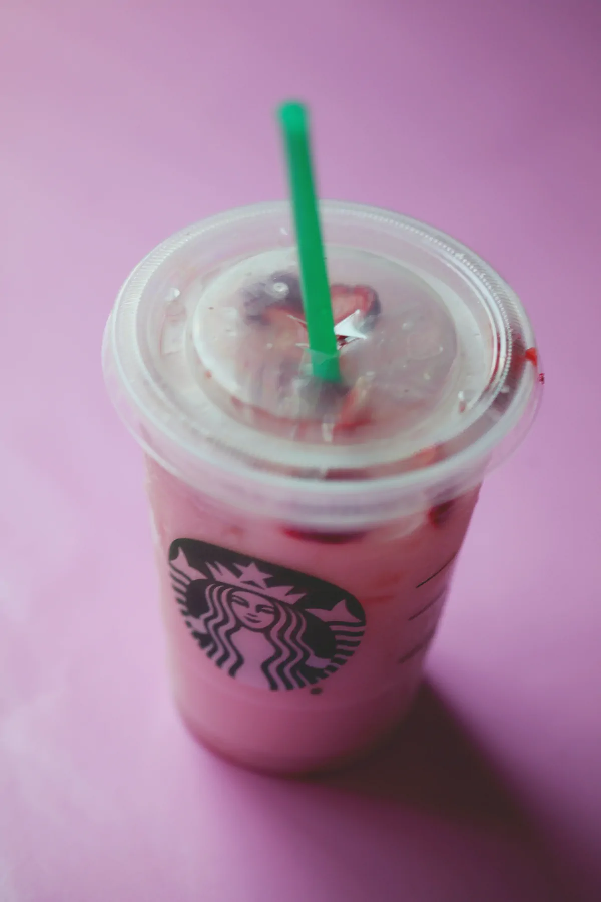 Pink drink in a disposable Starbucks plastic takeaway cup.