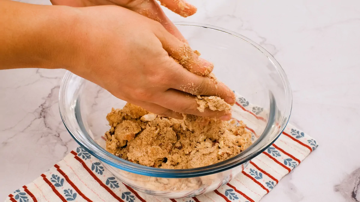 Gently mixing the crumbs with two hands in a glass bowl.
