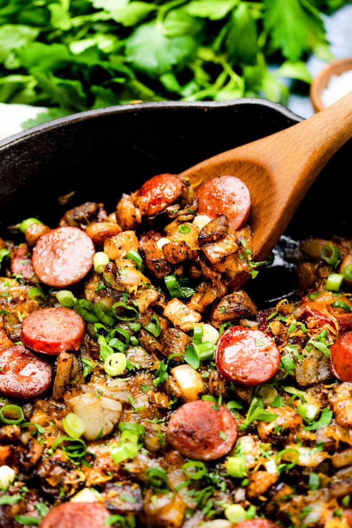 Keto Smoked Sausage Cheesy " Potatoes" in a cast iron skillet with spatula